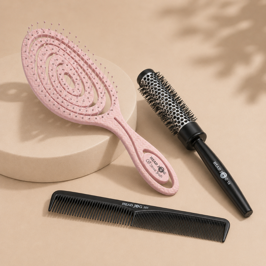 Head Jog hair styling tools featuring a pink vented brush, black round brush and styling comb, displayed on a neutral beige background.