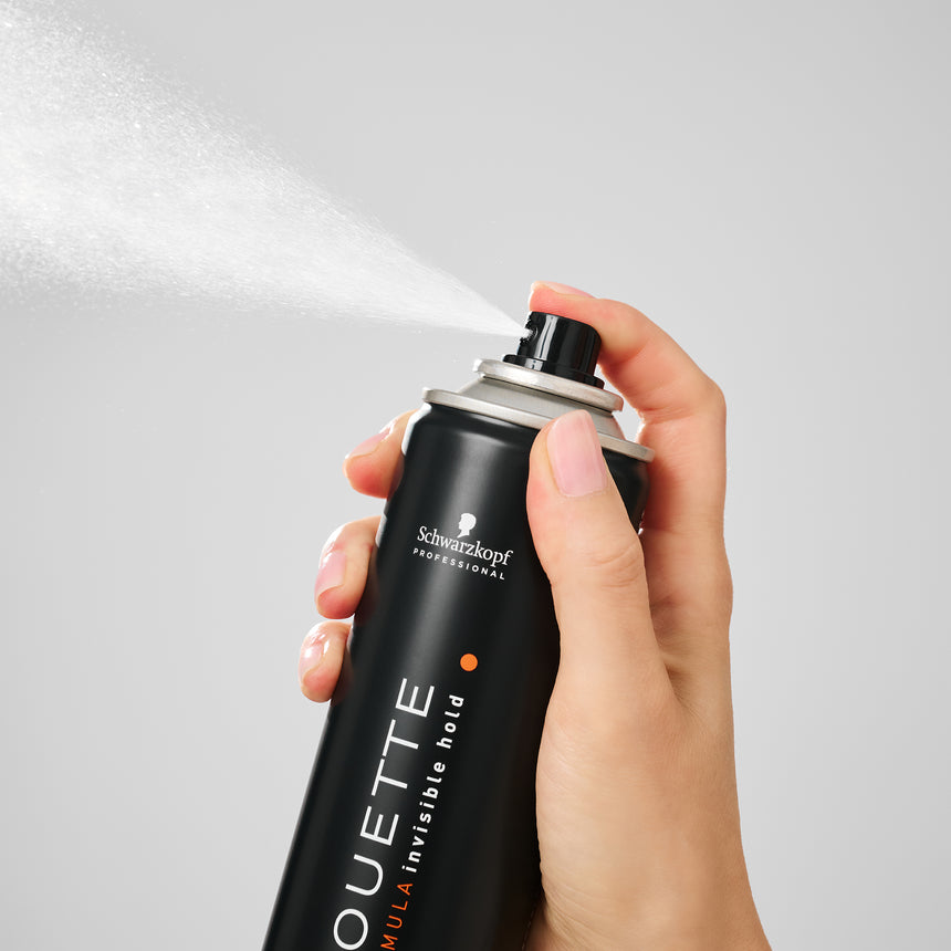 Hand holding Schwarzkopf Professional product in a minimalistic studio setting.