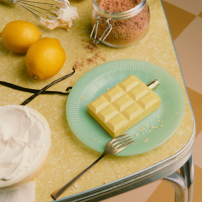 Sabrina Carpenter Lemon Pie Fragrance displayed on a turquoise plate and surrounded by scent-inspired elements.