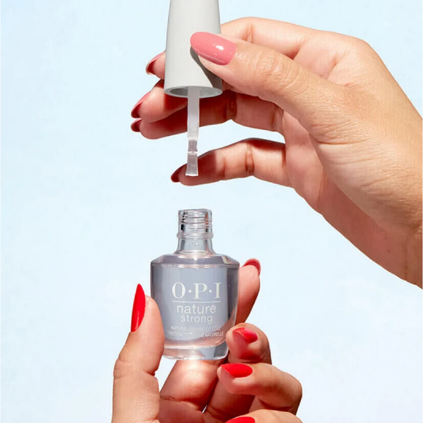 Hand holding OPI Nature Strong Top Coat against a minimalistic background.