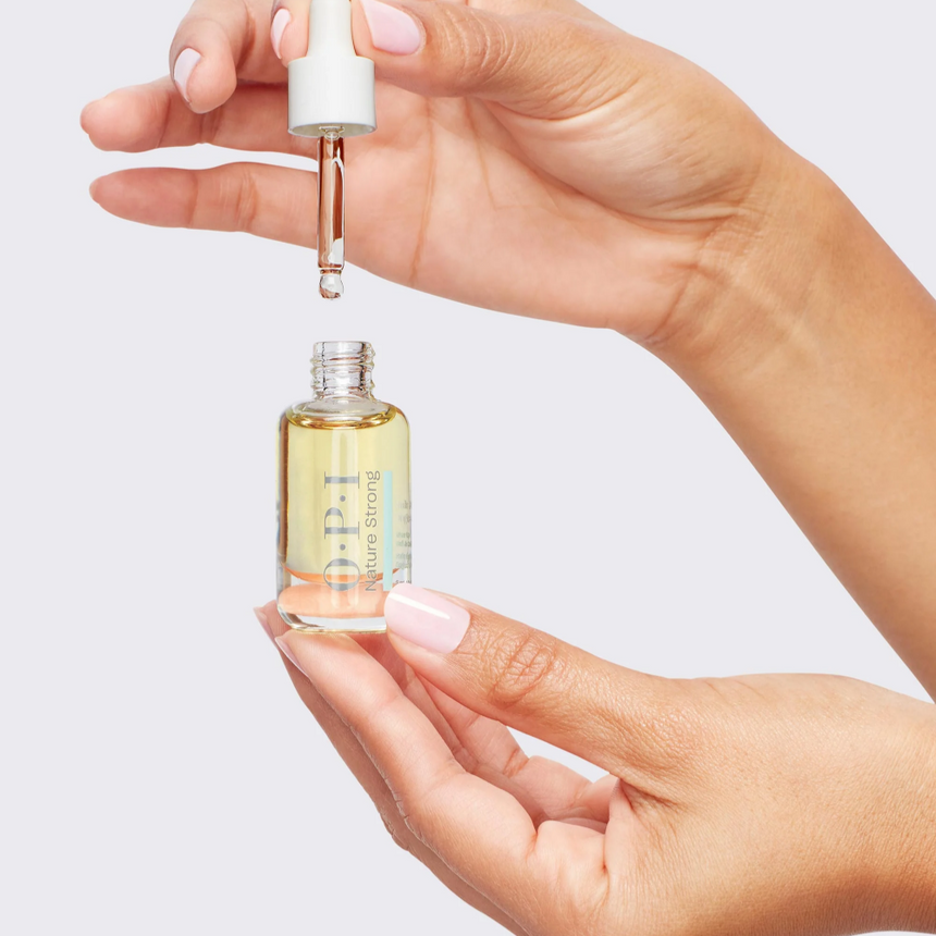 Hand holding the OPI Nature Strong Cuticle Oil bottle with a glass dropper against a white background.
