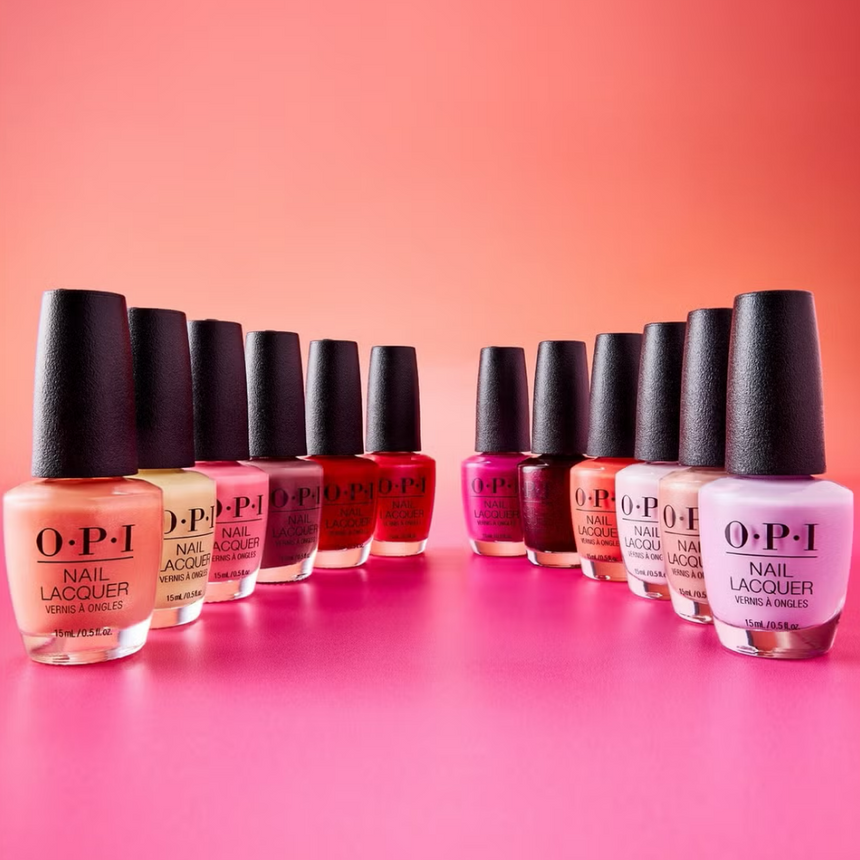A variety of OPI nail polishes displayed against a vibrant pink and orange ombre background.