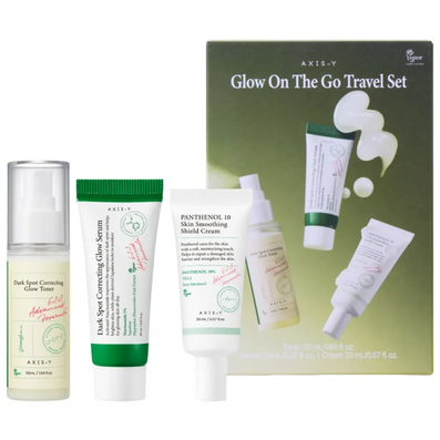 AXIS-Y Glow On The Go Travel Set featuring a dark green box and four skincare products: a serum bottle, a dark spot correcting glue serum tube, a pantenol 10 skin smoothing shield cream tube, and a toner bottle, arranged against a white background.