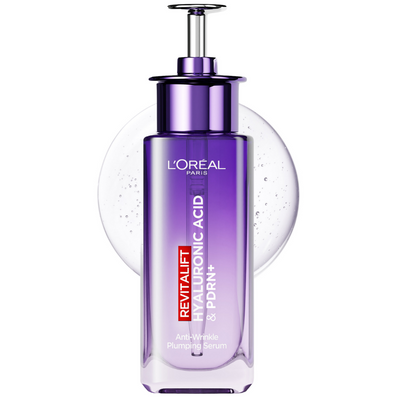 L'Oréal Paris Revitalift Plumping Serum in a purple glass bottle with a metallic pump dispenser, set against a white background with a translucent gel sphere behind it.