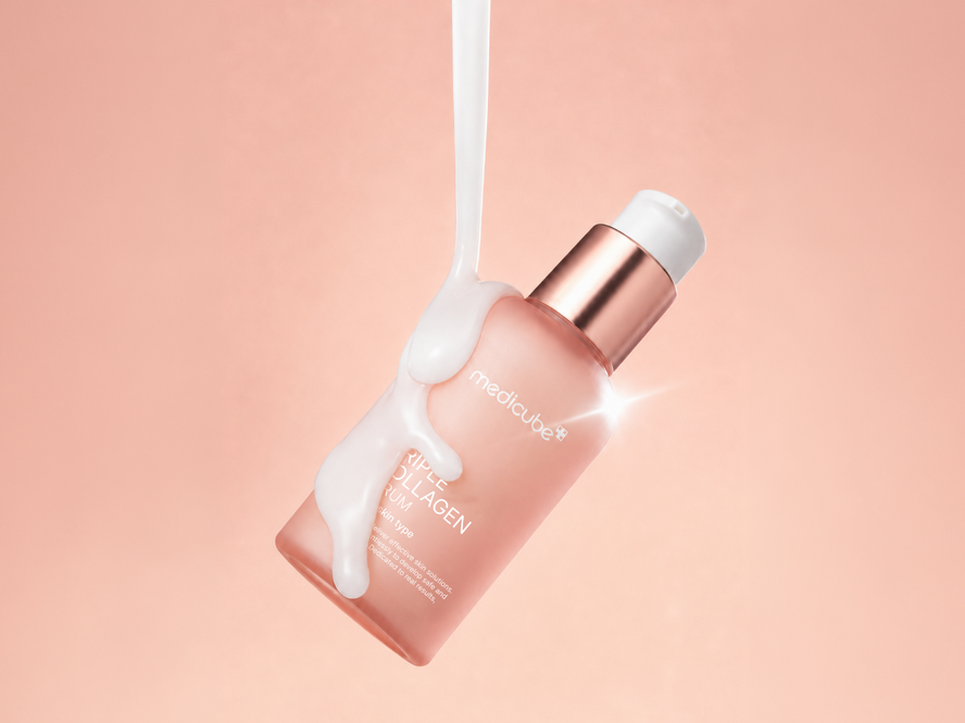 Medicube Triple Collagen Serum floating on a pink backdrop with product consistency falling