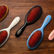 Mason Pearson Hair Brushes displayed in different colours against a wooden backdrop.