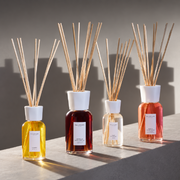 Millefiori reed diffusers displayed in sunlight against a neutral backdrop.