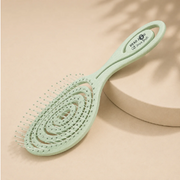 Head Jog pale green vented detangling hairbrush displayed on a neutral beige background.