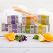 A variety of Little Soap Company products displayed with scent-inspired elements against a white wooden backdrop.