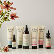 Sukin Haircare collection displayed with flowers against a neutral backdrop.