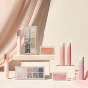 Rom&Nd makeup products, including eyeshadow palettes, blushes and lip tints, displayed on cream plinths against a soft neutral backdrop.
