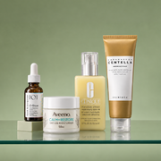 Geek & Gorgeous C-Glow Serum, Aveeno Calm + Restore Oat Gel Moisturiser, Clinique Dramatically Different Moisturising Lotion+ and SKIN1004 Madagascar Centella Ampoule Foam displayed on a soft green backdrop.