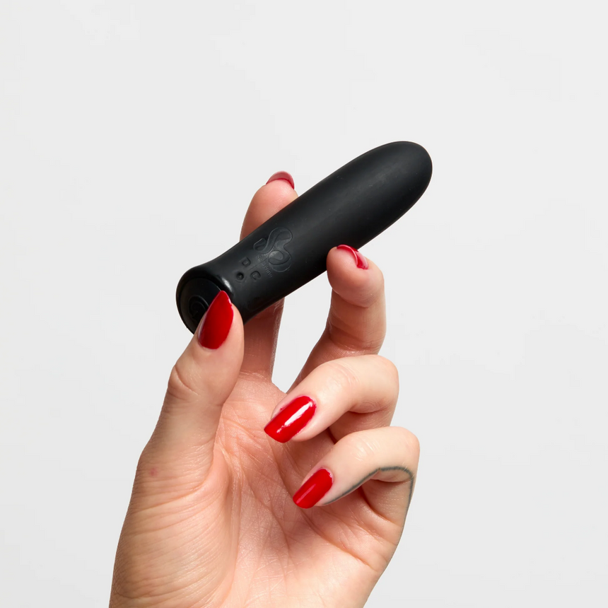 Hand holding So Divine Rechargeable Vibrating Wonder Bullet Black against a white studio backdrop.