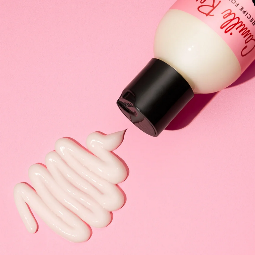 Camille Rose leave-in treatment displayed with a creamy product texture against a pink backdrop.