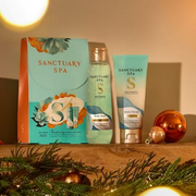 Sanctuary Spa body care gift set displayed with festive decorations, greenery and Christmas baubles.