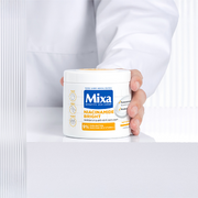 Mixa Niacinamide Bright Body Cream held in hand against a clean white clinical-inspired backdrop.