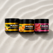 Three New In ProTan Solar Rush tanning creams in Pineapple, Citrus and Watermelon Burst displayed on white sand.
