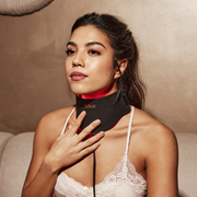 Woman wearing Silk'n LED light therapy  neck mask, with red light illuminated.

