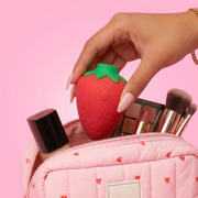 Hand holding So Divine Strawgasm Rechargeable Clitoral Suction Stimulator displayed with against a pink backdrop