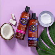 Hask Haircare Curl Care Shampoo and Conditioner displayed with coconut pieces and a tropical-inspired leaf against a purple backdrop.