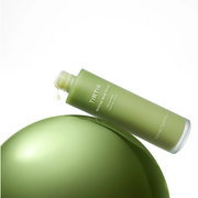 TirTir Matcha Ampoule Toner bottle in green packaging, displayed at an angle over a glossy green sphere on a white background.
