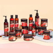 As I Am haircare products, including shampoos, conditioners, treatments and styling products, displayed on pastel platforms against a peach background.