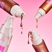 Multiple shades of 2BTanned Glow Drip Body Shimmer displayed against a pink radiant backdrop.