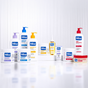 Mixa skincare range displayed on a clean white reflective backdrop, featuring creams, lotions and targeted treatments.
