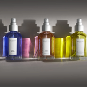 Millefiori home fragrance sprays displayed against a neutral backdrop with colourful light reflections.