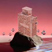 Rayhaan fragrance displayed on a dark rock with floating metallic spheres against a pink gradient background.