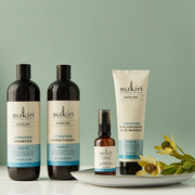 Sukin Hydrating Haircare collection displayed with botanical elements against a soft green backdrop.