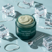 Heimish Marine Care Algae + Peptide Eye Cream displayed with melting ice cubes and an applicator against a light blue background.