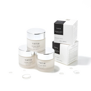 TIRTIR Ceramic Cream skincare jars and boxes displayed on a clean white background with water droplets.
