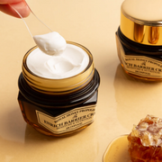 SKINFOOD Royal Honey Propolis Enrich Barrier Cream shown open with a scoop of moisturiser, alongside a second jar and honeycomb on a warm golden background.