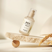 SkinFood Rice Brightening Serum displayed on a stone slab against a beige backdrop.