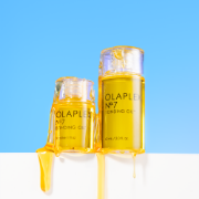Olaplex No.7 Bonding Oil bottles displayed with oil drips against a bright blue and white background.