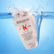 Kérastase Genesis shampoo displayed splashing through water against a bright blue background.