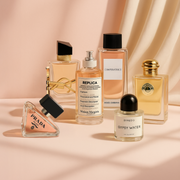 A selection of fragrances from YSL, Maison Margiela, Dolce & Gabbana, Prada, Burberry and Byredo displayed on a soft blush background.